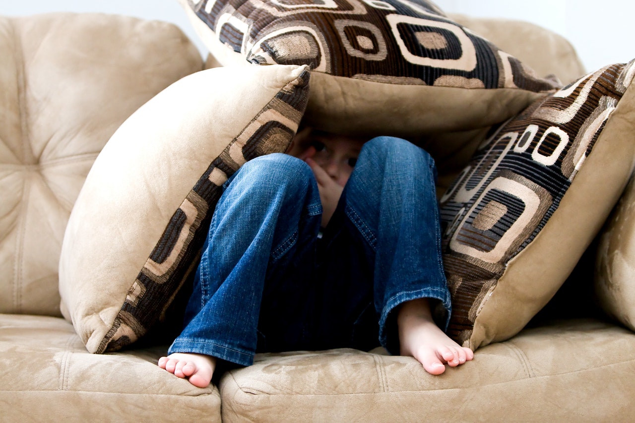 criança se escondendo no sofá